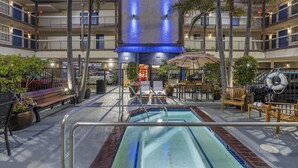 Ein Hotelatrium mit Schwimmbad, Sitzgelegenheiten im Freien und Palmen.