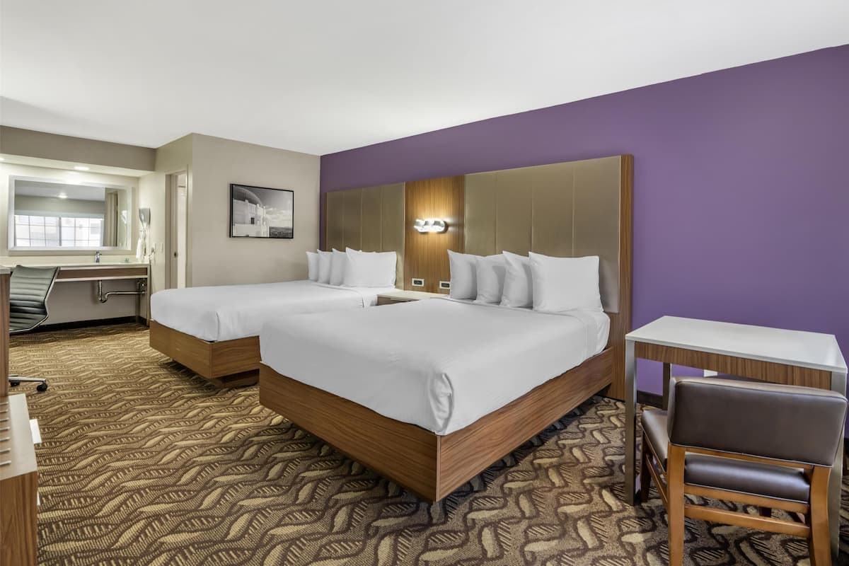 Ein Hotelzimmer mit zwei Betten, einem Schreibtisch und einem Stuhl.