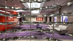 A hotel lobby with a modern design, featuring a central seating area with sofas and a patterned carpet. - Hilton Long Beach Hotel (Long Beach)