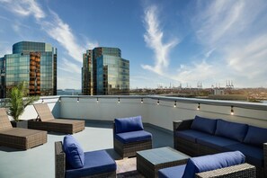 A rooftop terrace with wicker furniture and a city view.