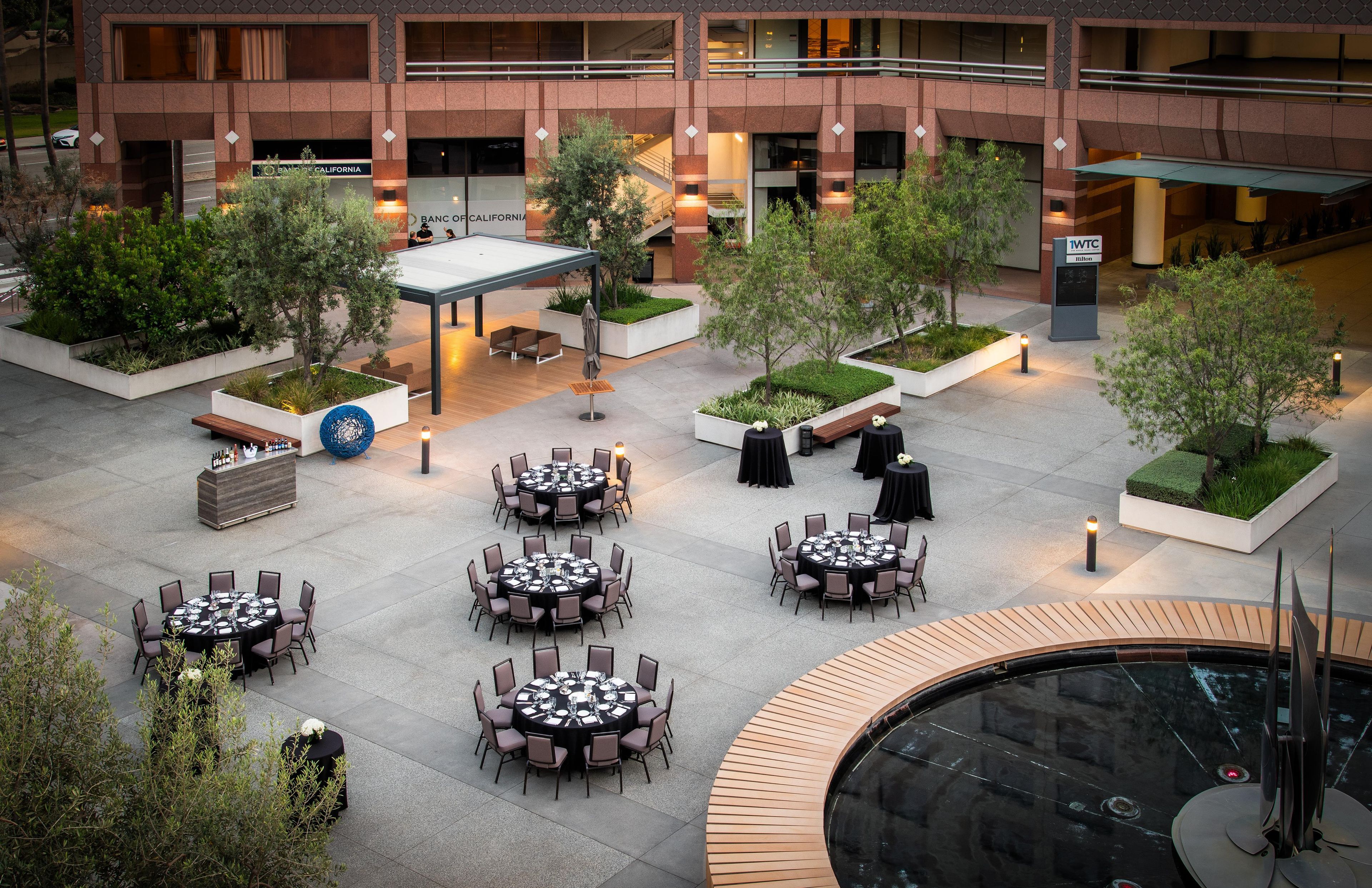 Un patio de hotel con mobiliario exterior, una fuente y un jardín ajardinado.