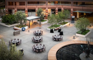 A hotel courtyard with outdoor seating, a fountain, and a landscaped garden. - Hilton Long Beach Hotel (Long Beach)