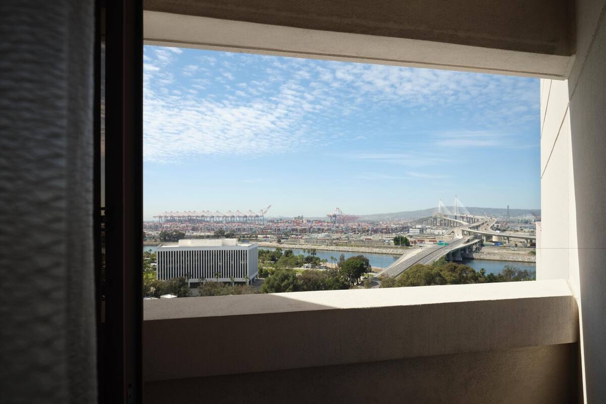 A view through a window of a cityscape with a bridge, buildings, and a body of water.