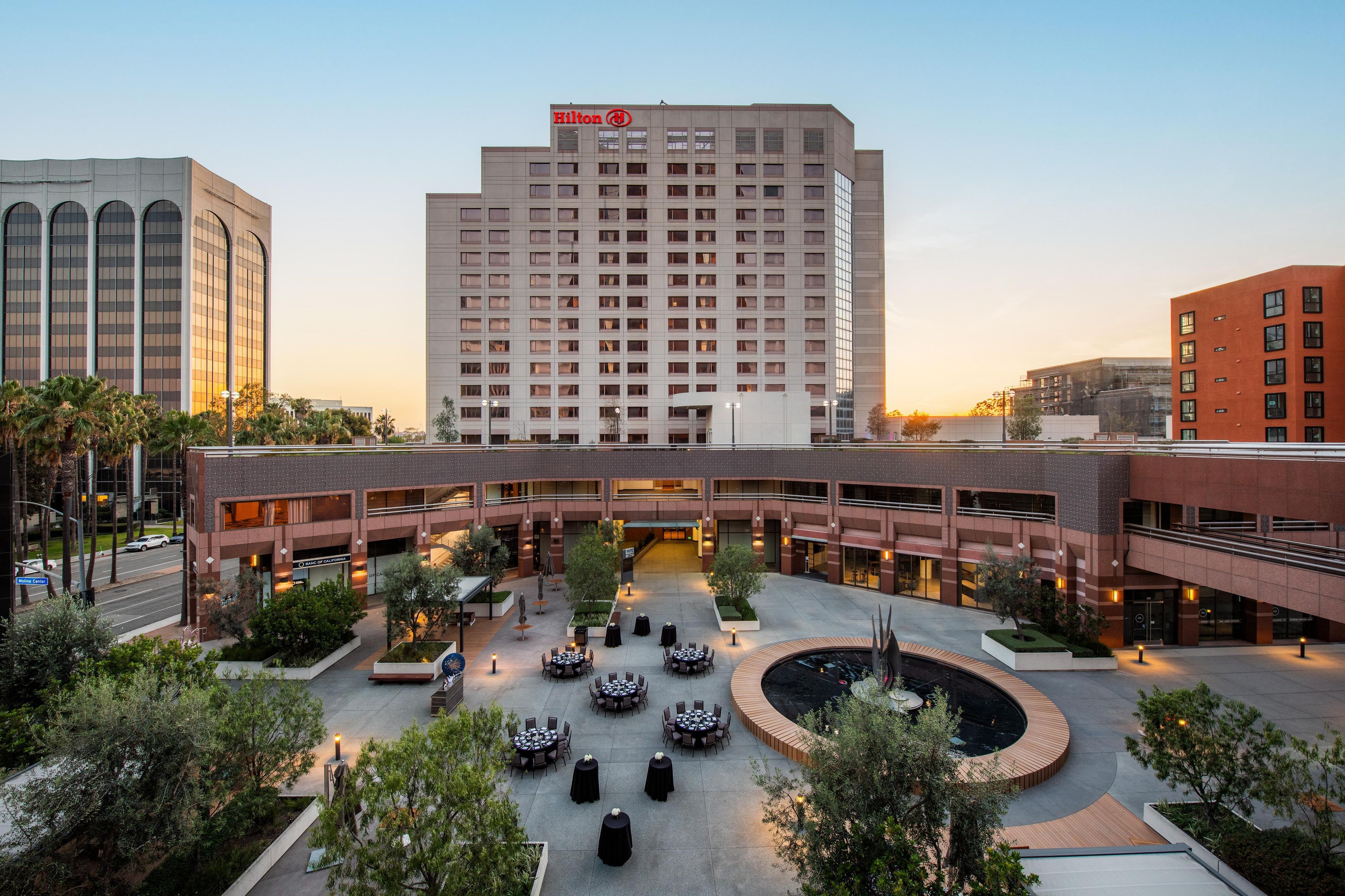Un hotel con patio central, mesas al aire libre y piscina.