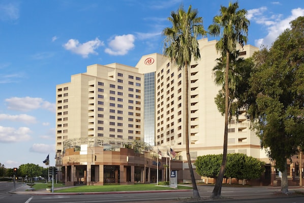 A hotel with multiple floors, a prominent glass building, and palm trees.