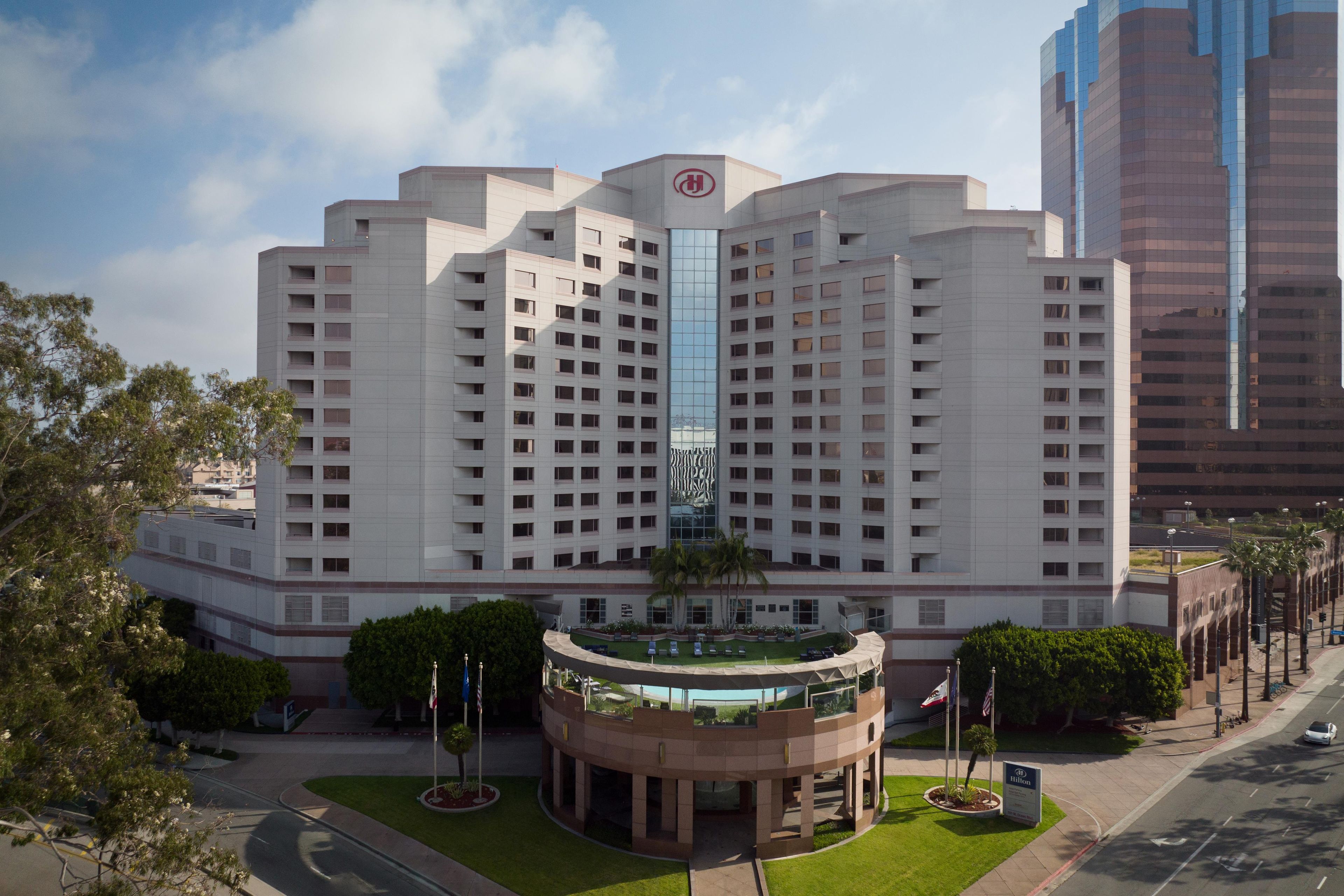 Un hotel de varios pisos con un patio central, asta de banderas y cielo despejado.