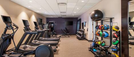 A gym with treadmills, weight machines, and a variety of exercise balls.