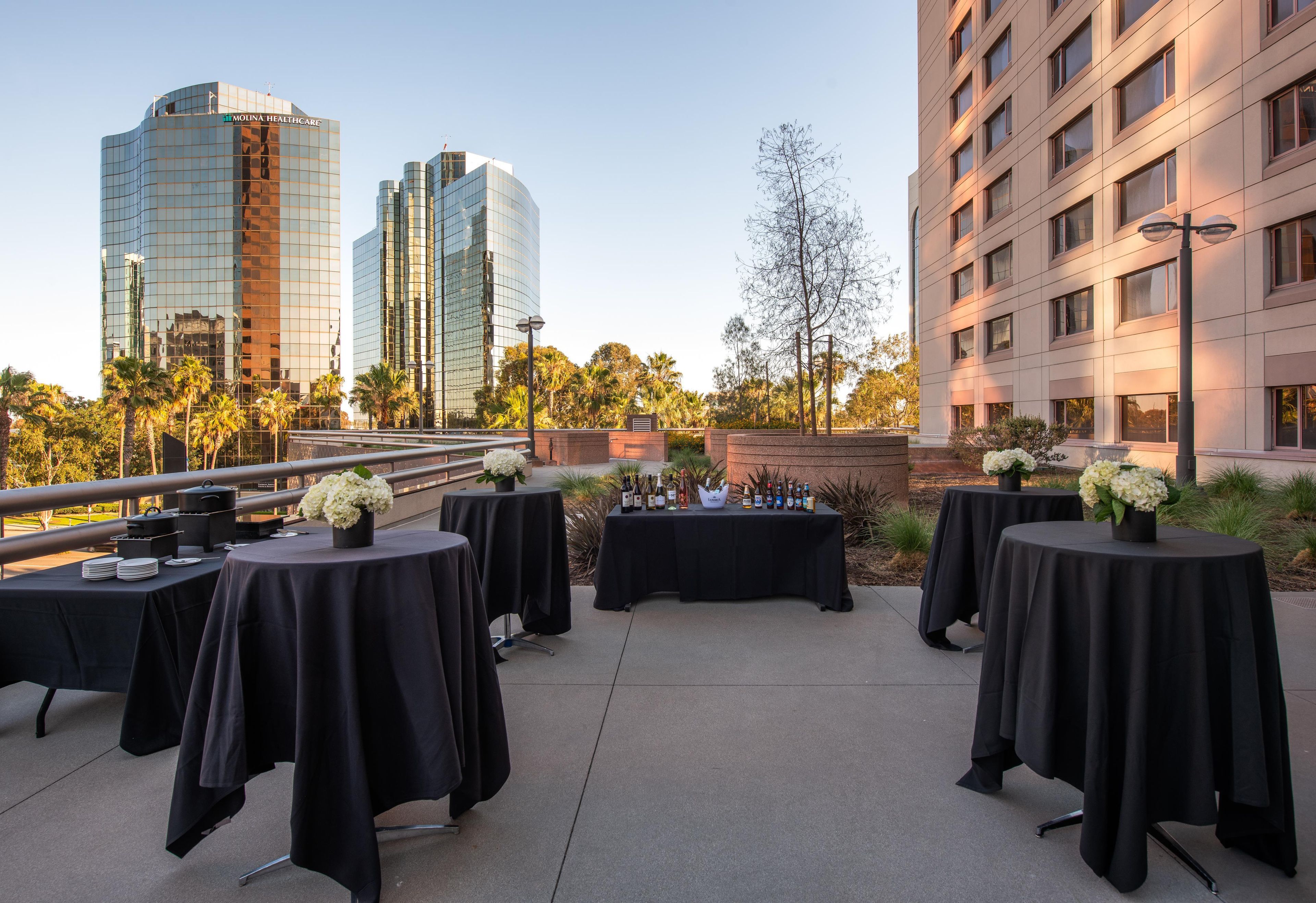 An outdoor patio with tables set up for dining, overlooking a cityscape with modern buildings.