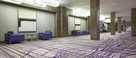 Un vestíbulo de hotel espacioso con alfombra estampada, zonas de estar y grandes pilares.
