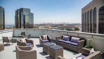 A rooftop terrace with wicker furniture and a view of the cityscape.