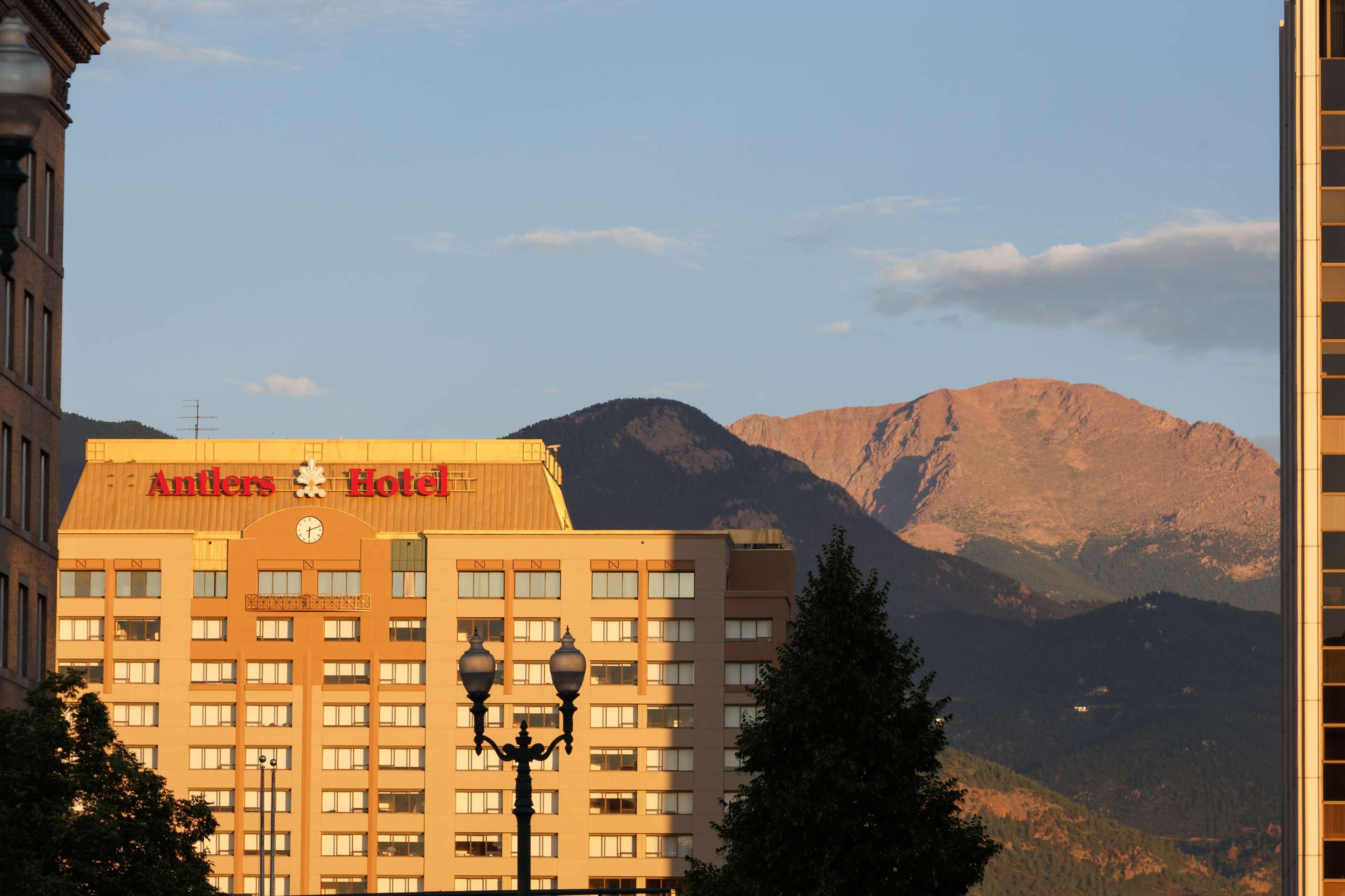 A hotel with a prominent sign, multiple floors, and a mountainous backdrop.