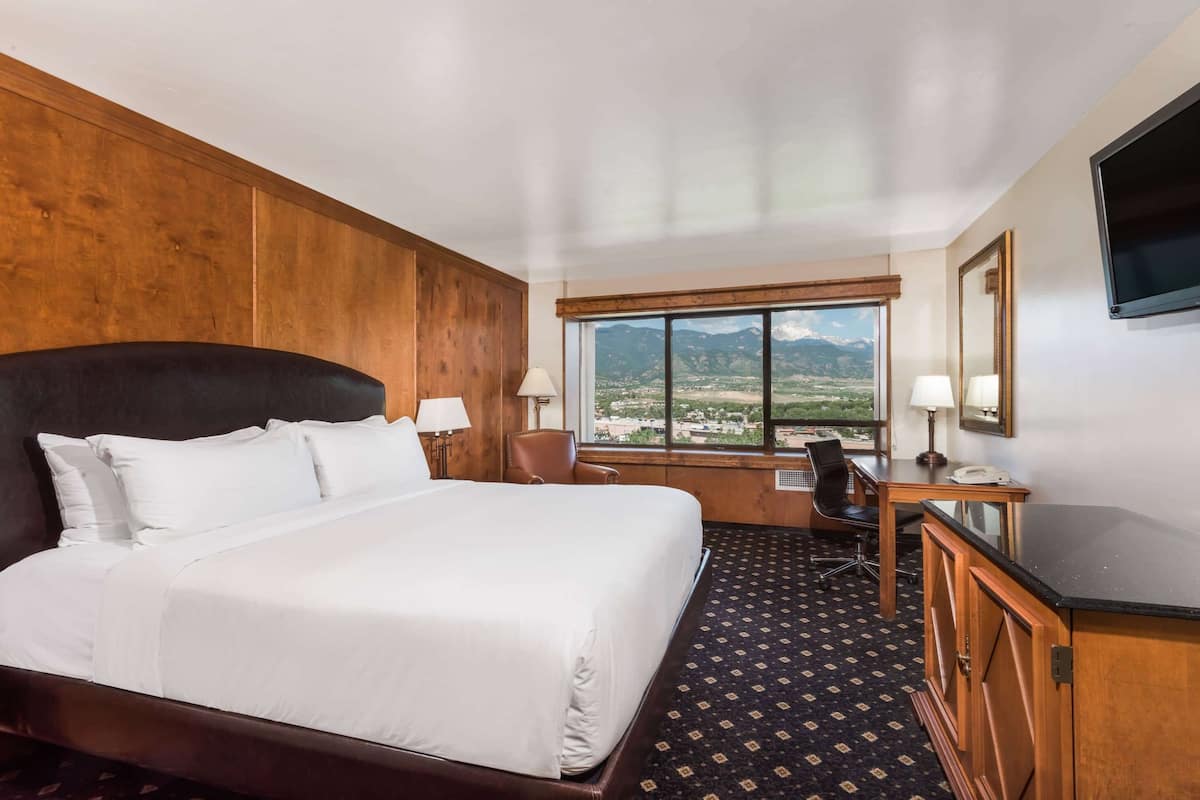 A hotel room with a large bed, a desk, a chair, and a TV.