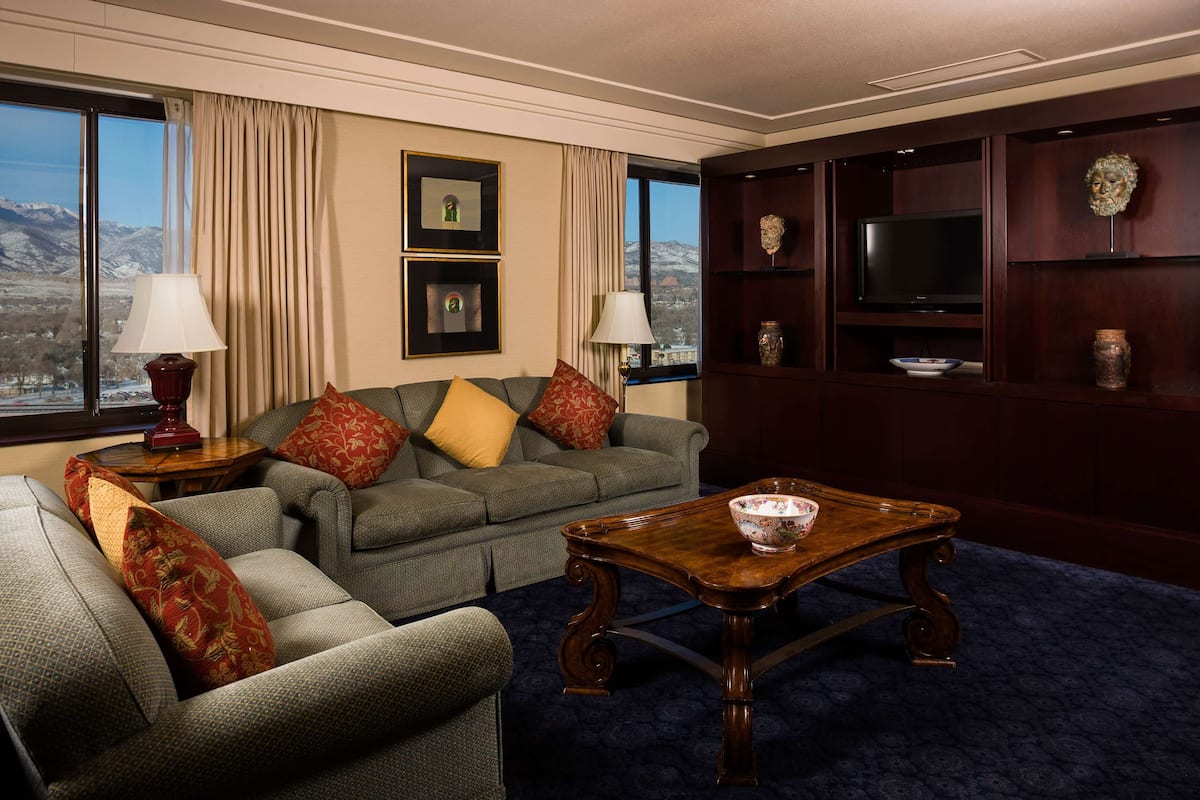 A living room with a sofa set, a coffee table, a television, and a bookshelf.