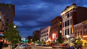 A city street at night with various buildings, including a restaurant with a red sign and a bank with a prominent sign.