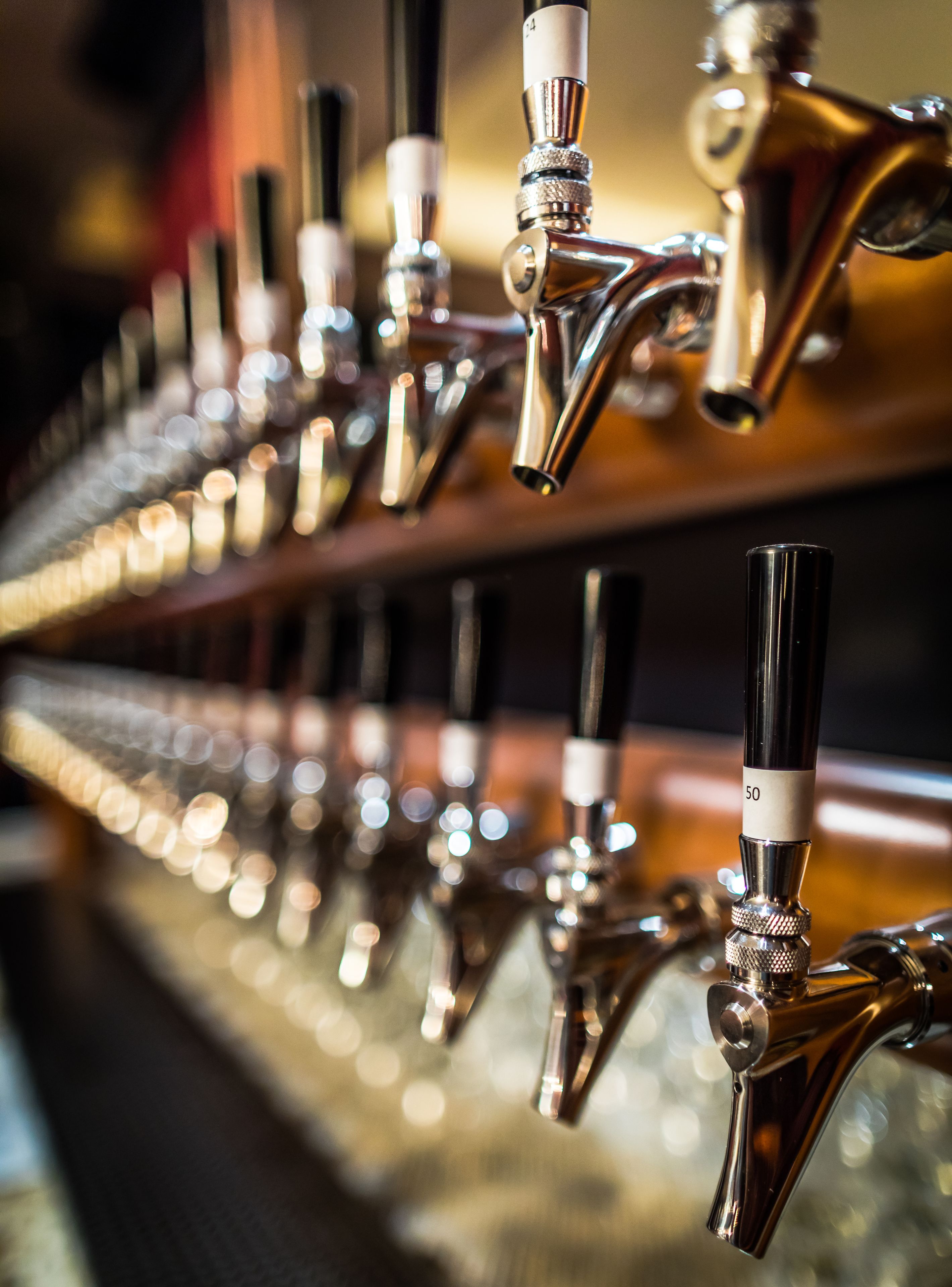 A row of beer taps with labels, likely in a bar or pub setting.