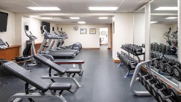 A gym with treadmills, weight benches, and a rack of dumbbells.