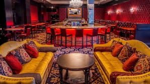 A bar area with a central bar, multiple seating arrangements, and a chandelier.
