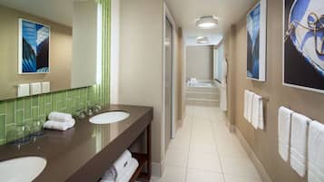 Bathroom features a long vanity with two sinks, a large mirror, and a green-tiled backsplash.