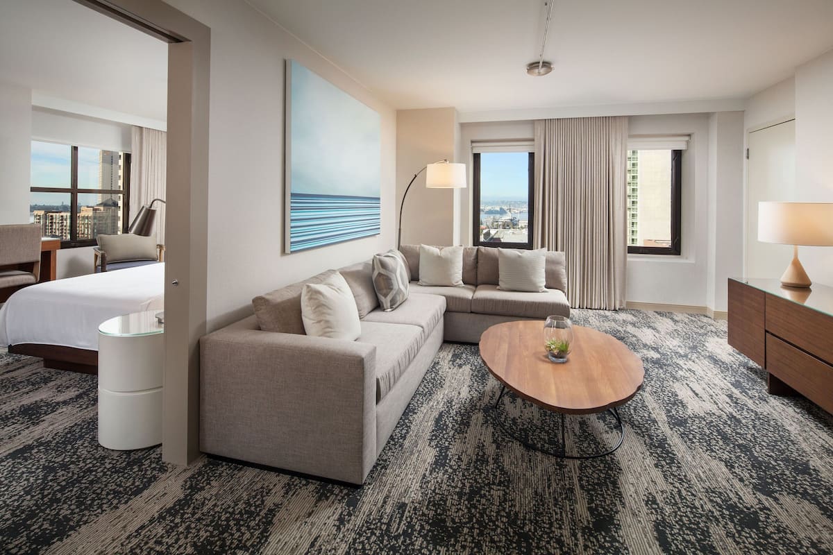 Una habitación de hotel moderna con cama, sofá y una mesa de centro redonda.
