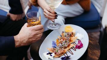 A person holding a glass of whiskey and a martini glass with a clear liquid.