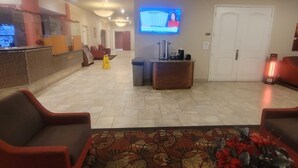 A hotel lobby with a reception desk, seating area, and a television screen. - Ramada by Wyndham Sacramento (Sacramento)