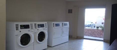 A laundry room with two front-loading washing machines and a dryer.