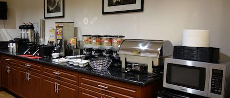 Una cocina con estación de café, microondas y armarios.