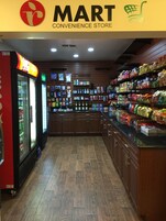 Interior de una tienda de conveniencia con secciones refrigeradas, estantes llenos de bocadillos y una variedad de productos envasados.