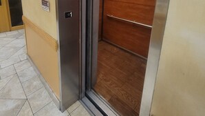 An elevator with a metallic interior and a wooden panel on the right side. - Ramada by Wyndham Sacramento (Sacramento)