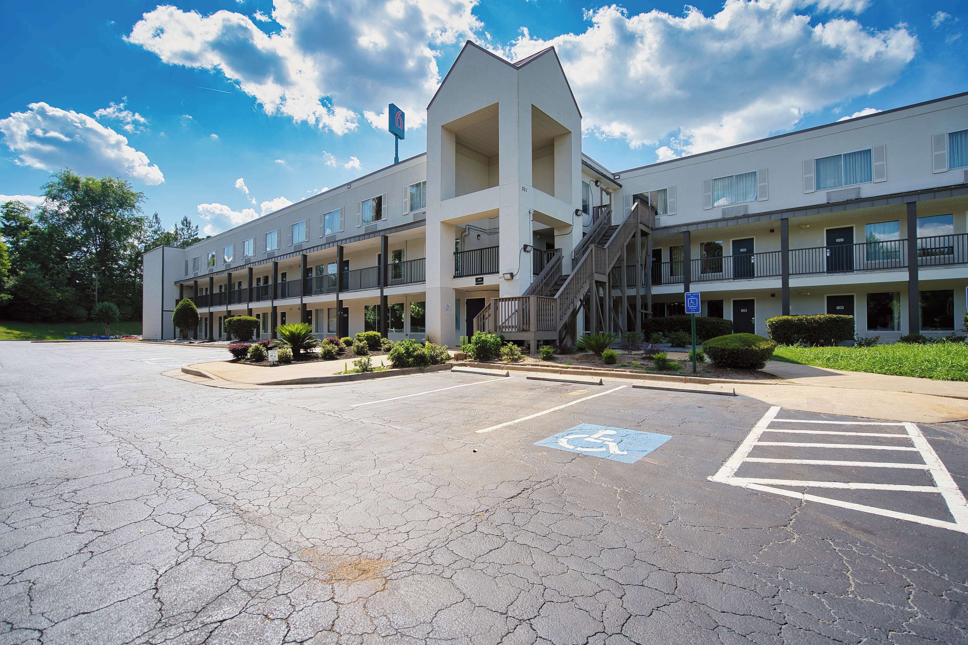 A multi-story hotel with a parking lot, wheelchair accessibility, and a staircase leading to the entrance.