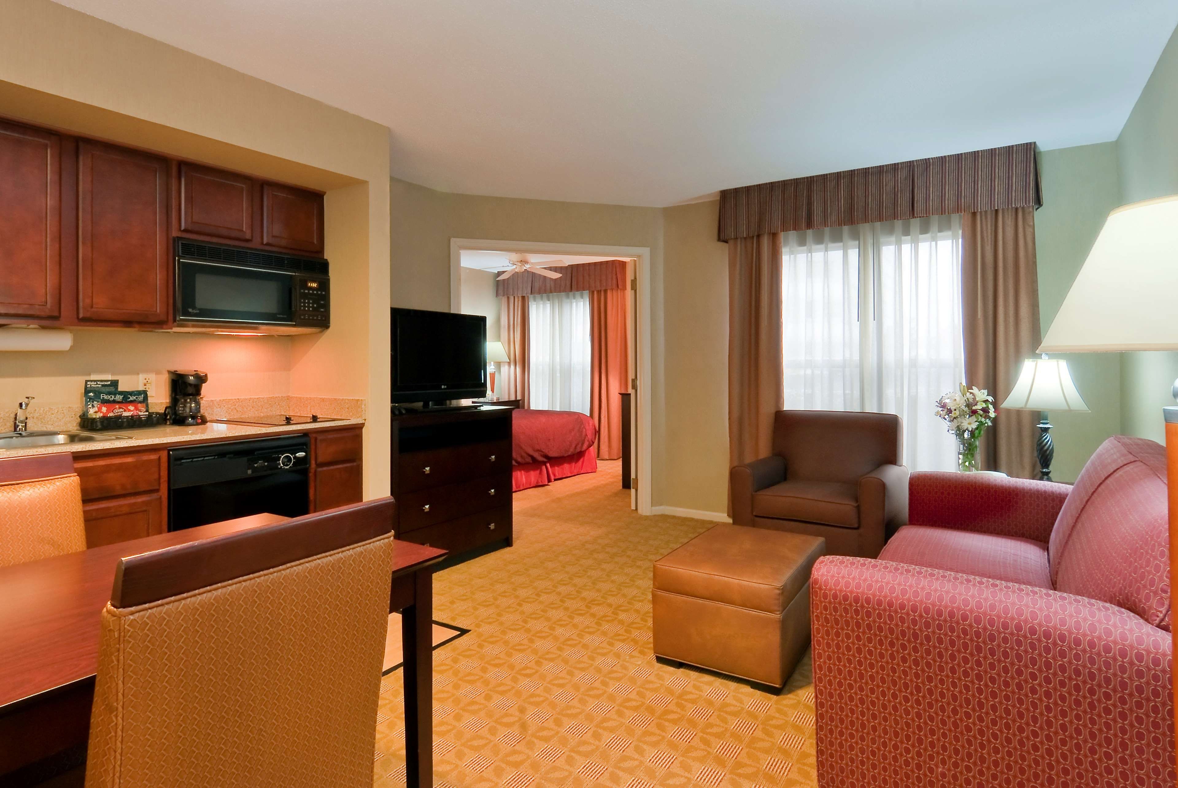 Une chambre d’hôtel équipée d’une kitchenette, d’une télévision, d’un canapé, d’un fauteuil et d’un lit.