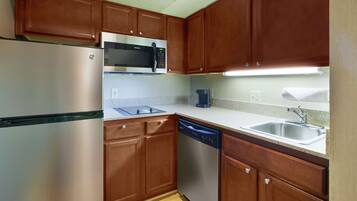 A compact kitchen with a refrigerator, microwave, coffee maker, dishwasher, and a sink.