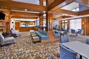 A hotel lobby with a seating area, a bar, and a view of the kitchen.