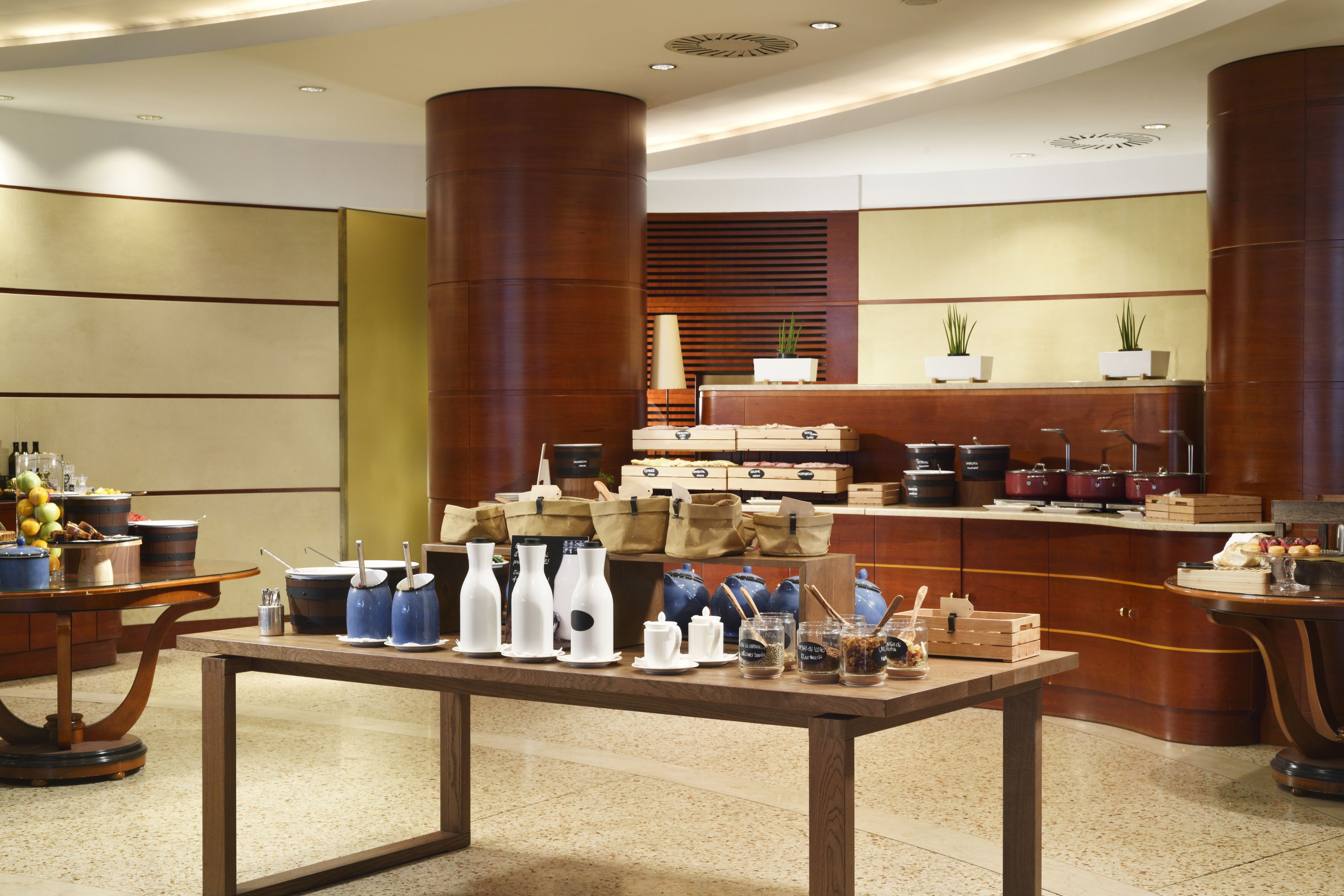 A modern kitchen with a central island, wooden cabinets, and a variety of kitchenware and appliances.