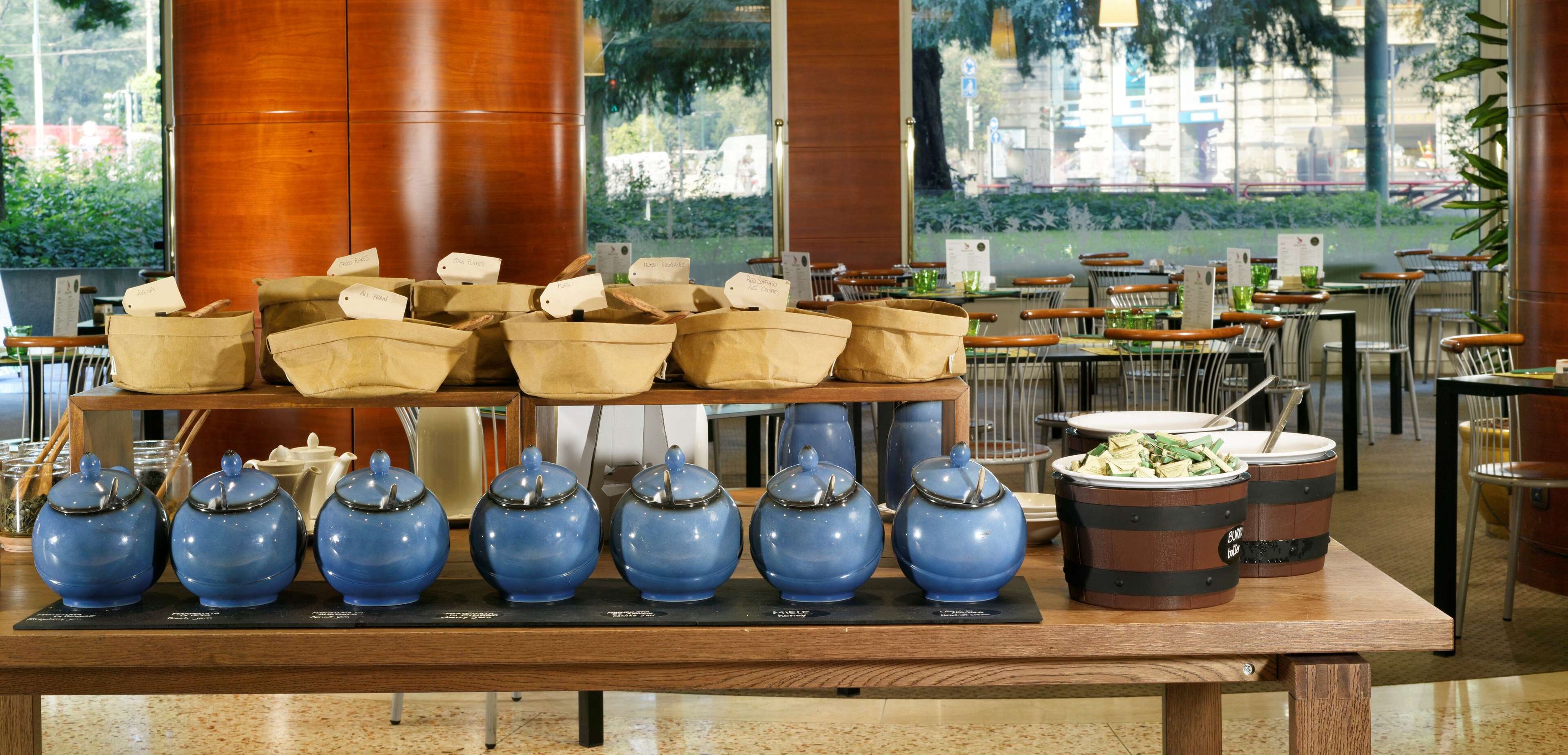 Un buffet avec différents plats présentés dans des récipients variés et accompagné des ustensiles nécessaires.