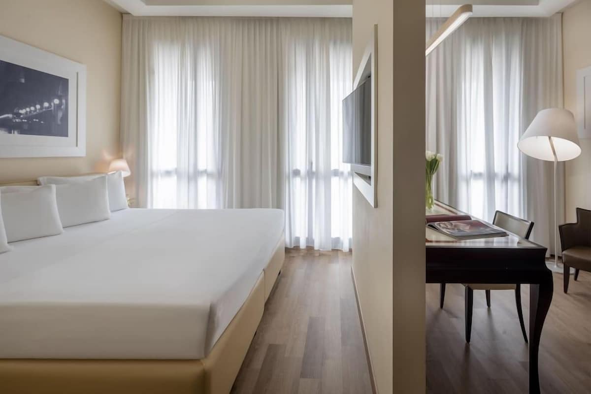 A hotel room with a bed, a desk, and a chair.