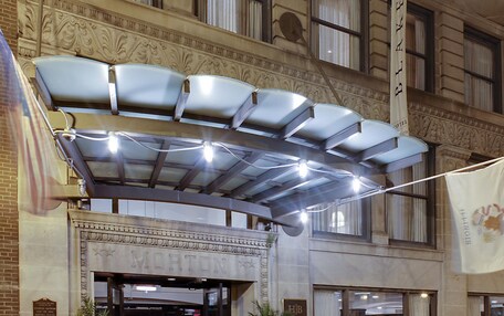 A hotel entrance with a marquee and string lights above the entrance.