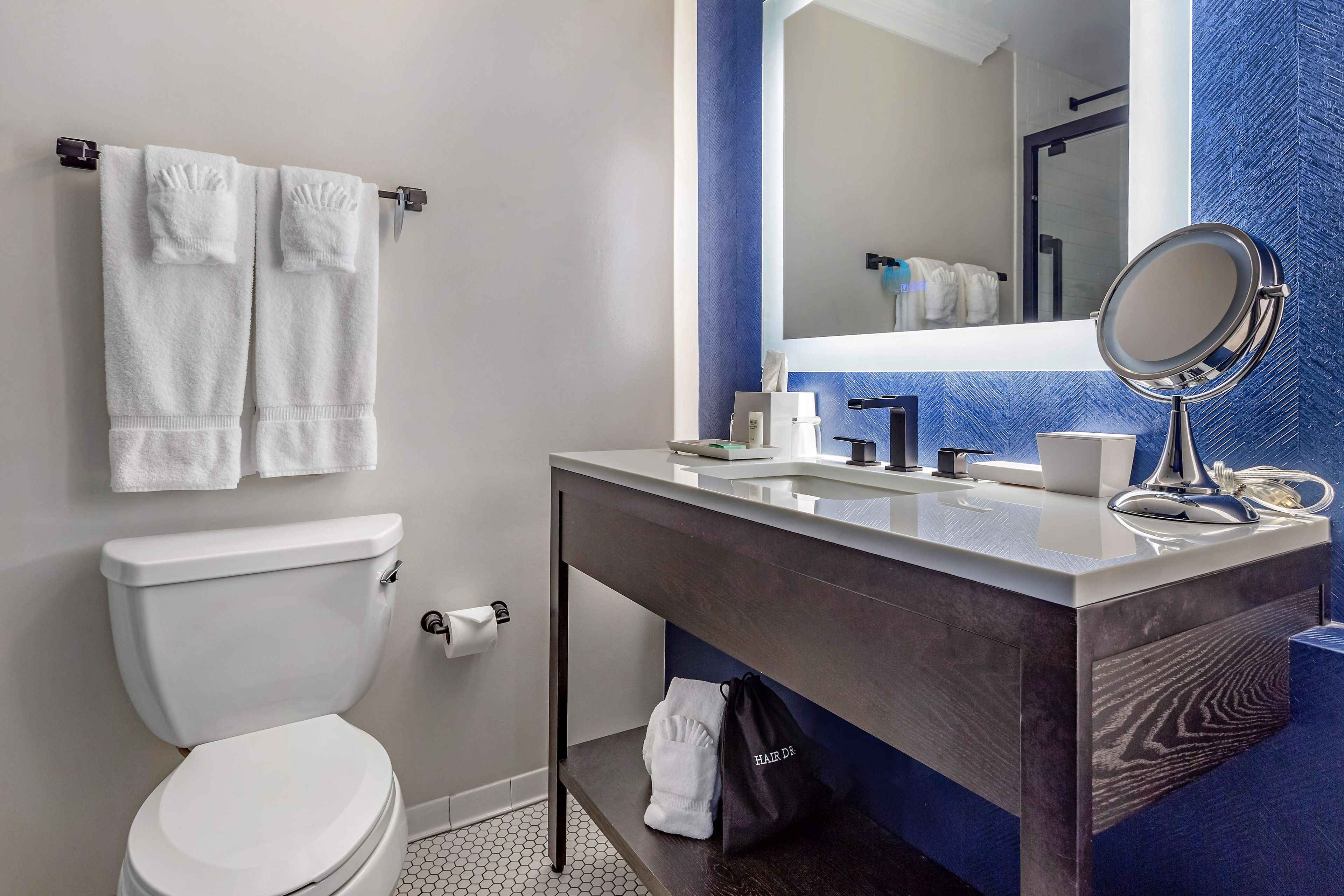 A modern bathroom with a toilet, sink, and mirror.