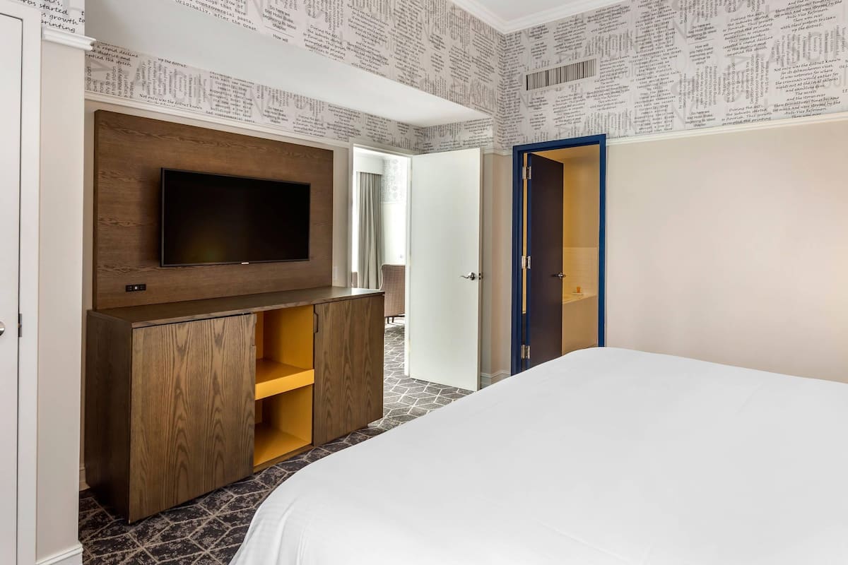 Un dormitorio con televisión instalada en un mueble de madera, una cama y un armario.