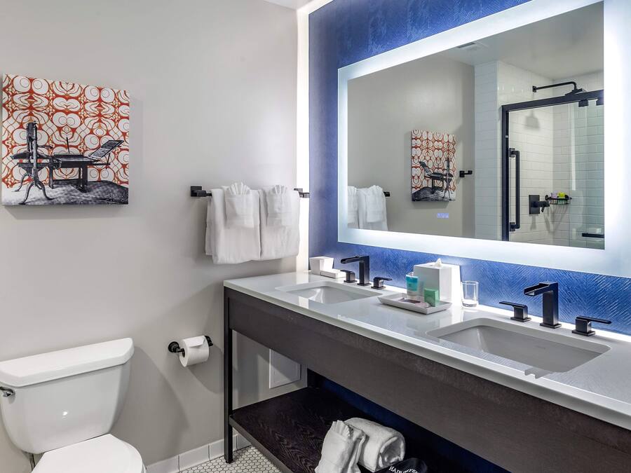 Un bagno moderno con un mobile lavabo doppio, uno specchio grande e un water.