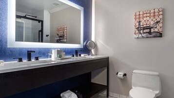 A modern bathroom with a large mirror, a white toilet, and a dark vanity.
