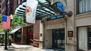 A hotel entrance with a classic facade, an American flag, and a sign for Hotel Blake Chicago. - Hilton Vacation Club Hotel Blake Chicago (Chicago)