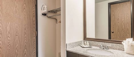 A bathroom with a wooden door, a sink with a mirror, and towel racks.