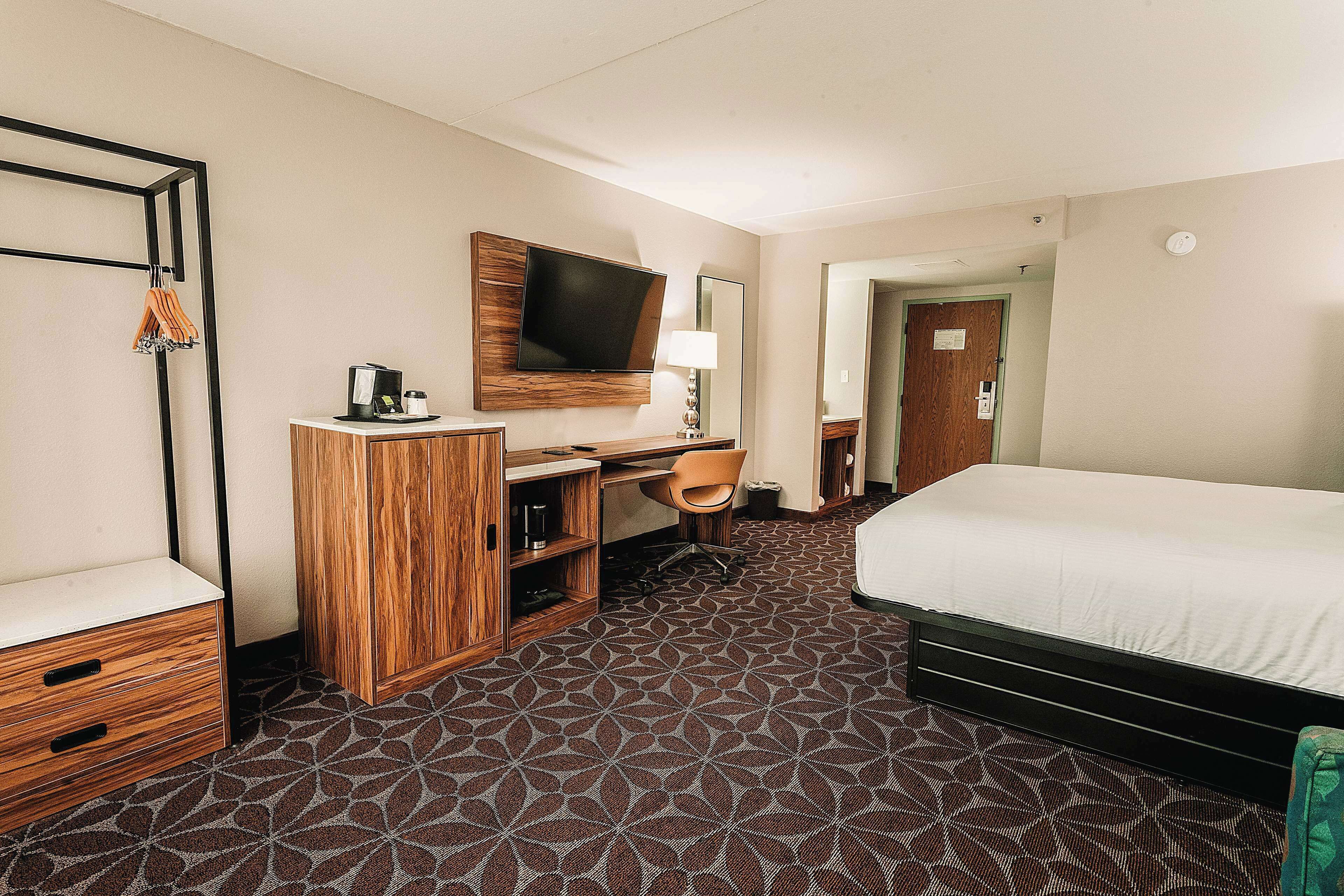 Une chambre d’hôtel comprenant un lit, un bureau avec une chaise, une télévision et une armoire.