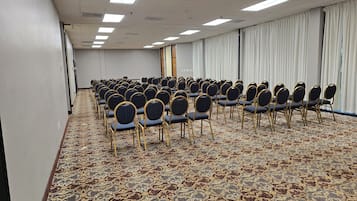 A conference room with rows of chairs, a patterned carpet, and a plain wall with a door.