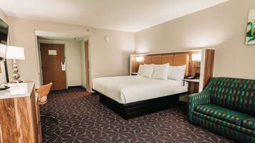 A hotel room with a bed, a desk, a chair, and a couch.
