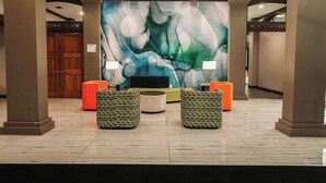 A lobby with a large abstract mural, two seating areas with patterned cushions, and a sign indicating 'Town Room' and 'North Elevation'.