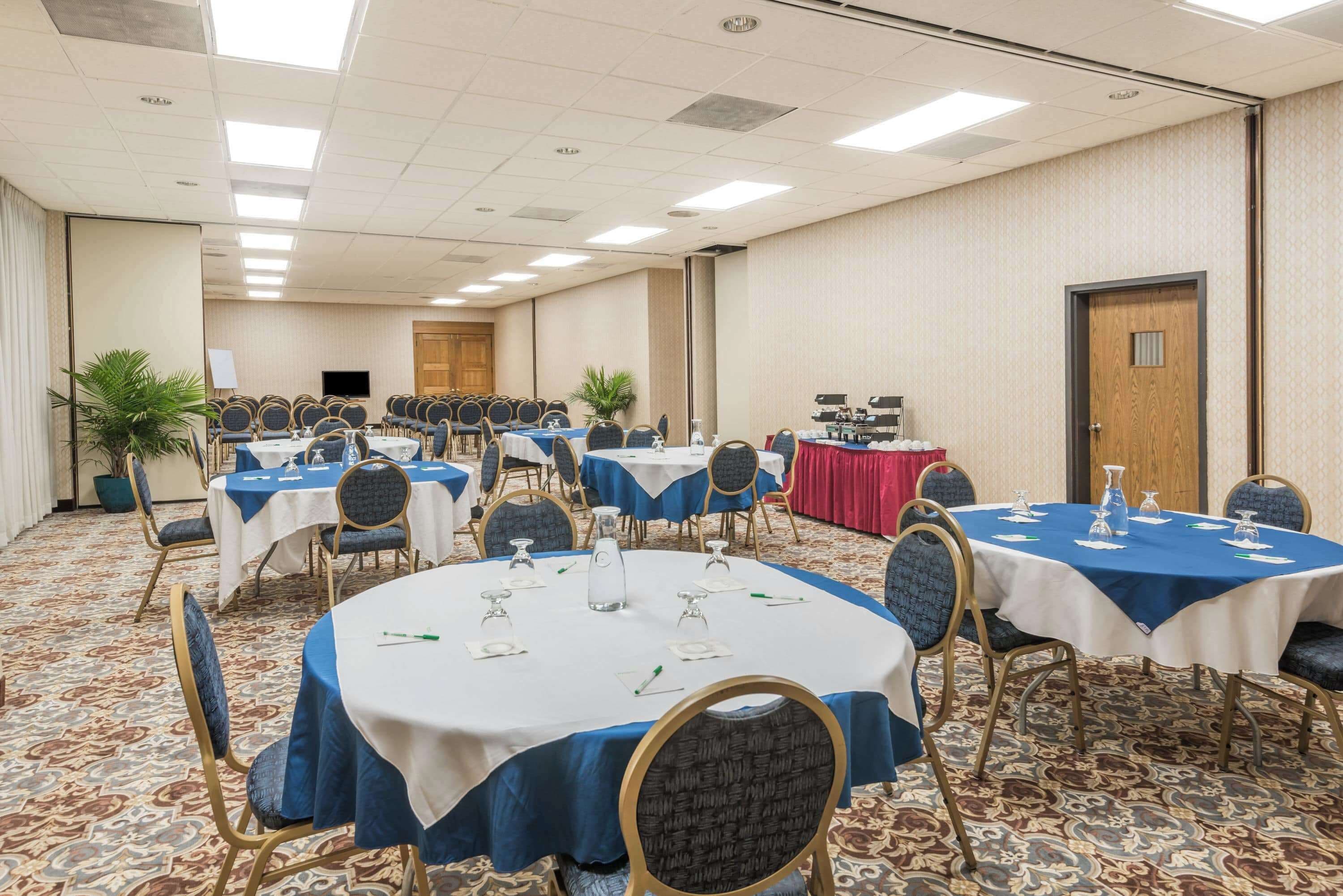 A conference room with round tables, chairs, and a stage area.