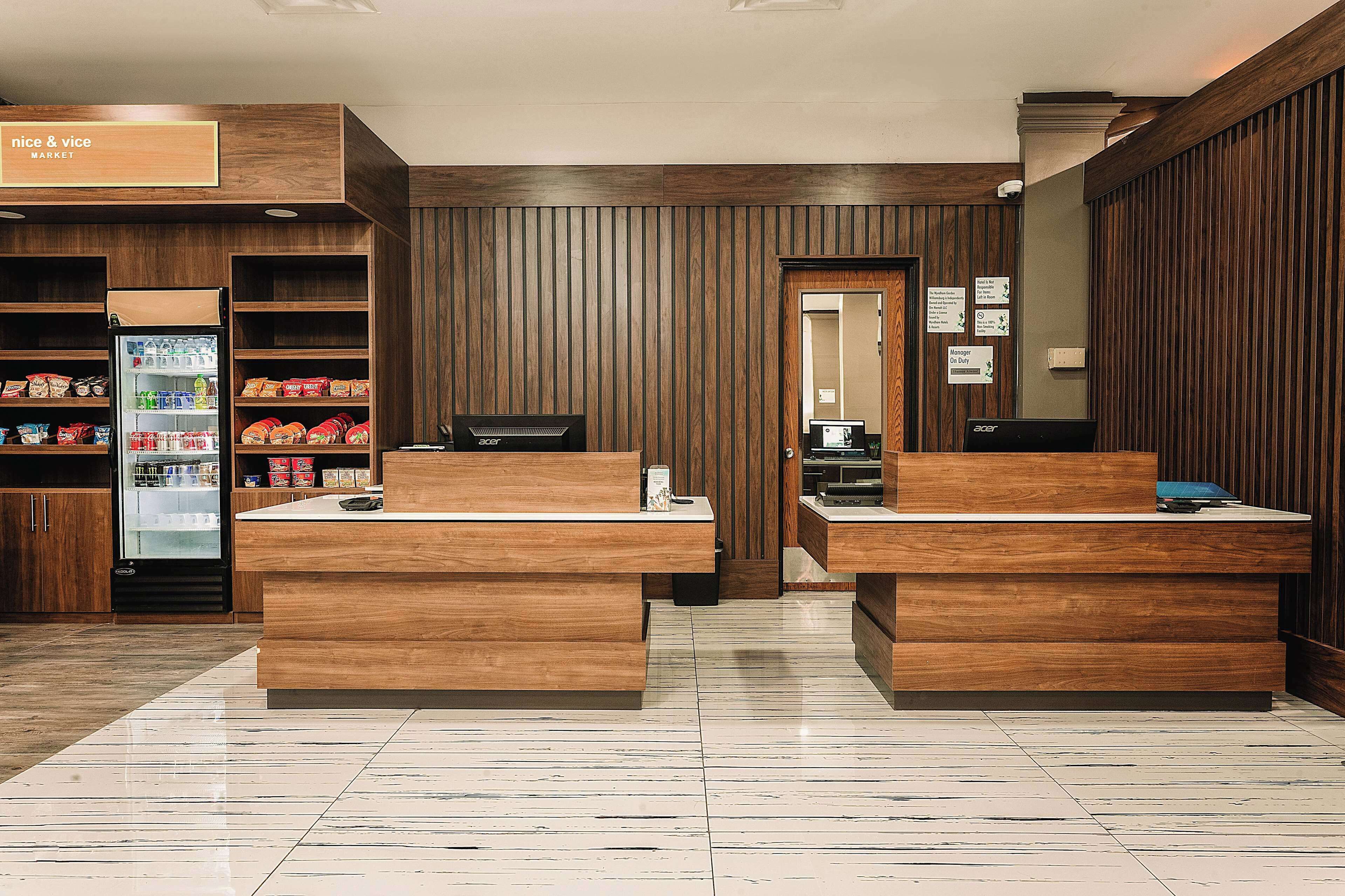 Un área de recepción con mostradores de madera, un refrigerador lleno de refrigerios y un letrero que dice "nice & vice MARKET".