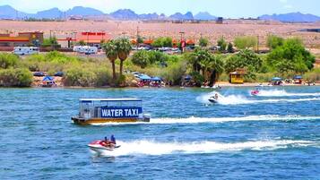 A water taxi service on a lake with a rental shop and a desert landscape in the background.
